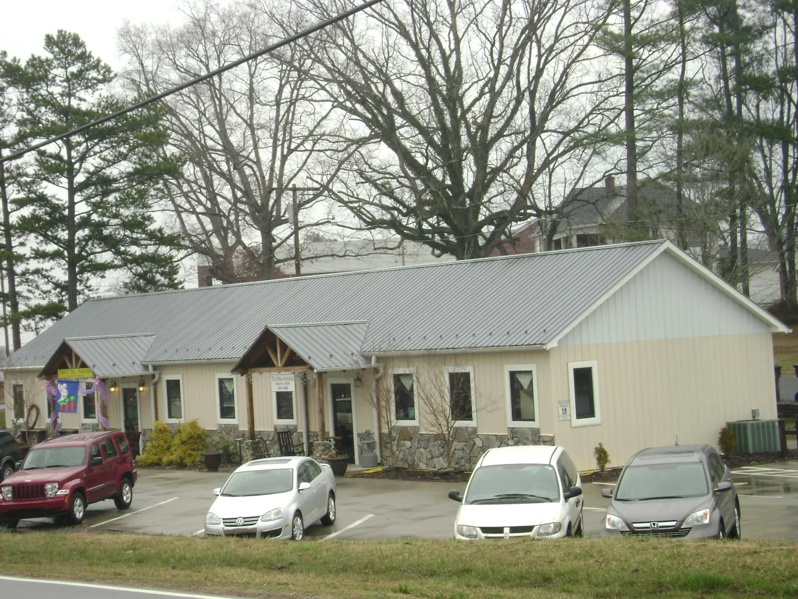 Gray metal roof with timber entry brackets on a small commercial building in Holy Cross