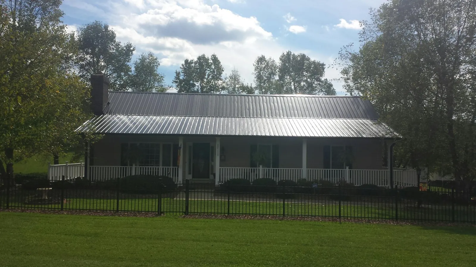 Gray metal roof on a brick ranch with a full width front porch — Gutter Guard Installation work by our crew in Holy Cross