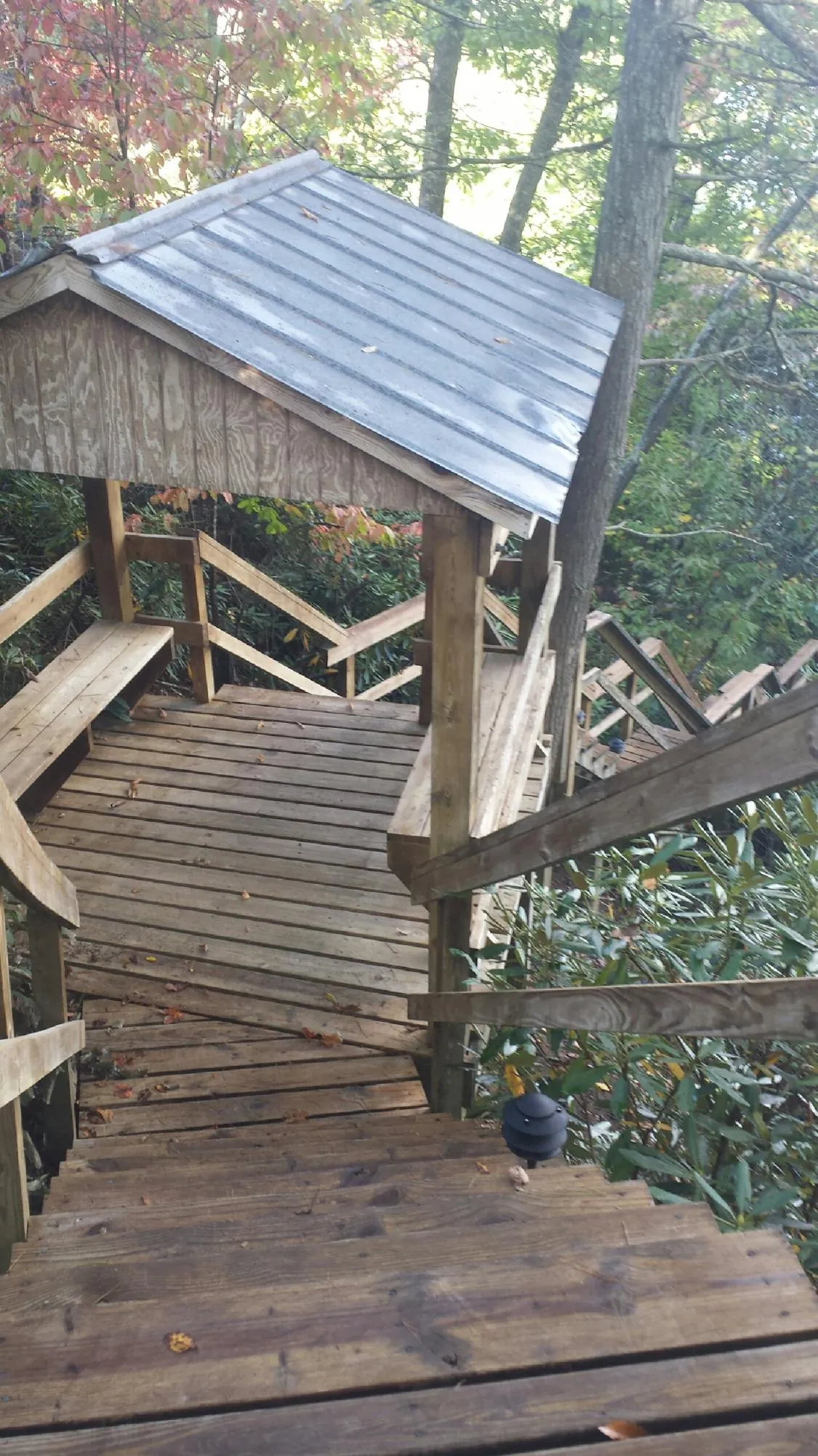 Metal roofed shelter over wooden steps on a wooded walkway — Skylight Repair & Installation work by our crew in Holy Cross